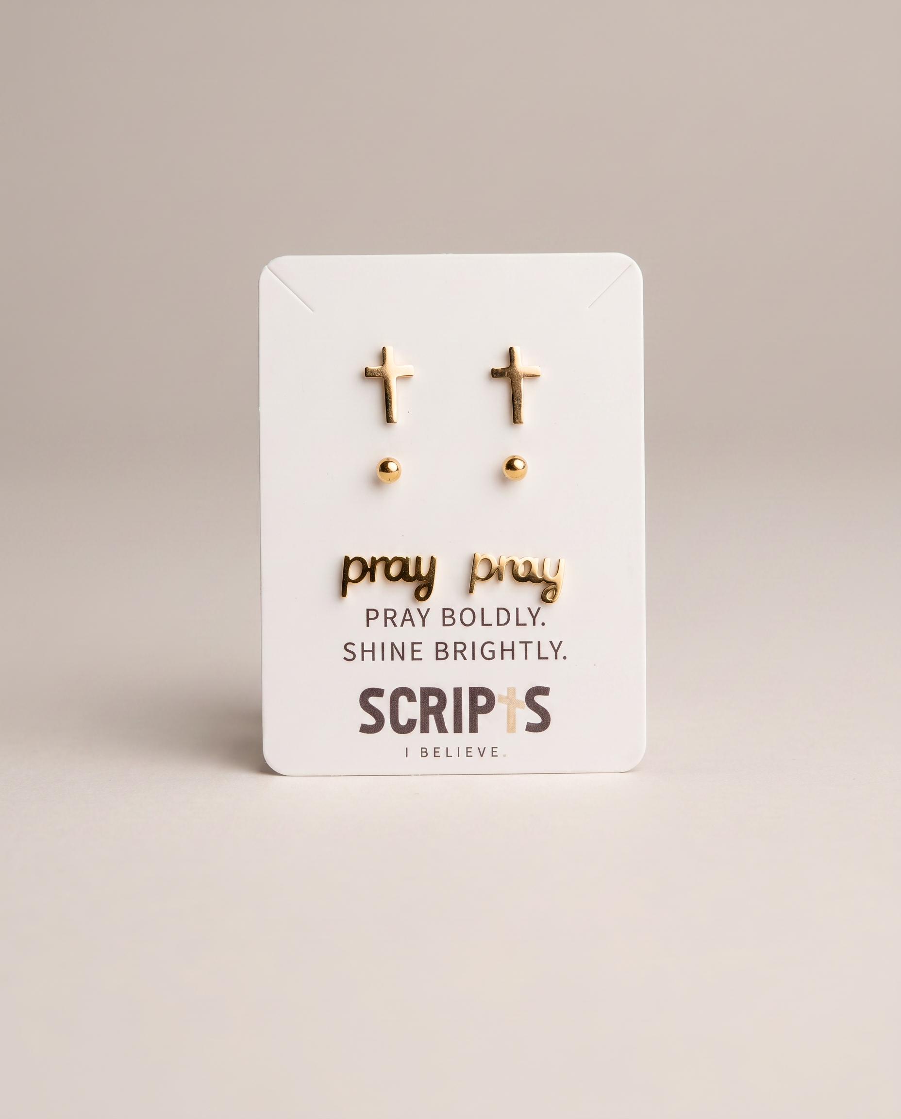 Gold cross stud earrings on Christian brand packaging