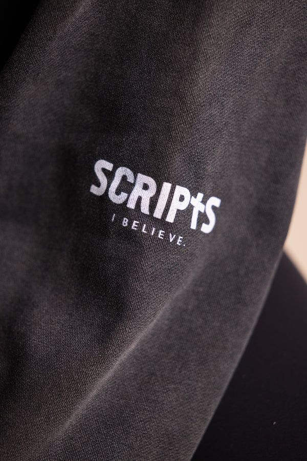 Close-up of black fleece fabric with "SCRIPTS, I Believe" embroidered logo