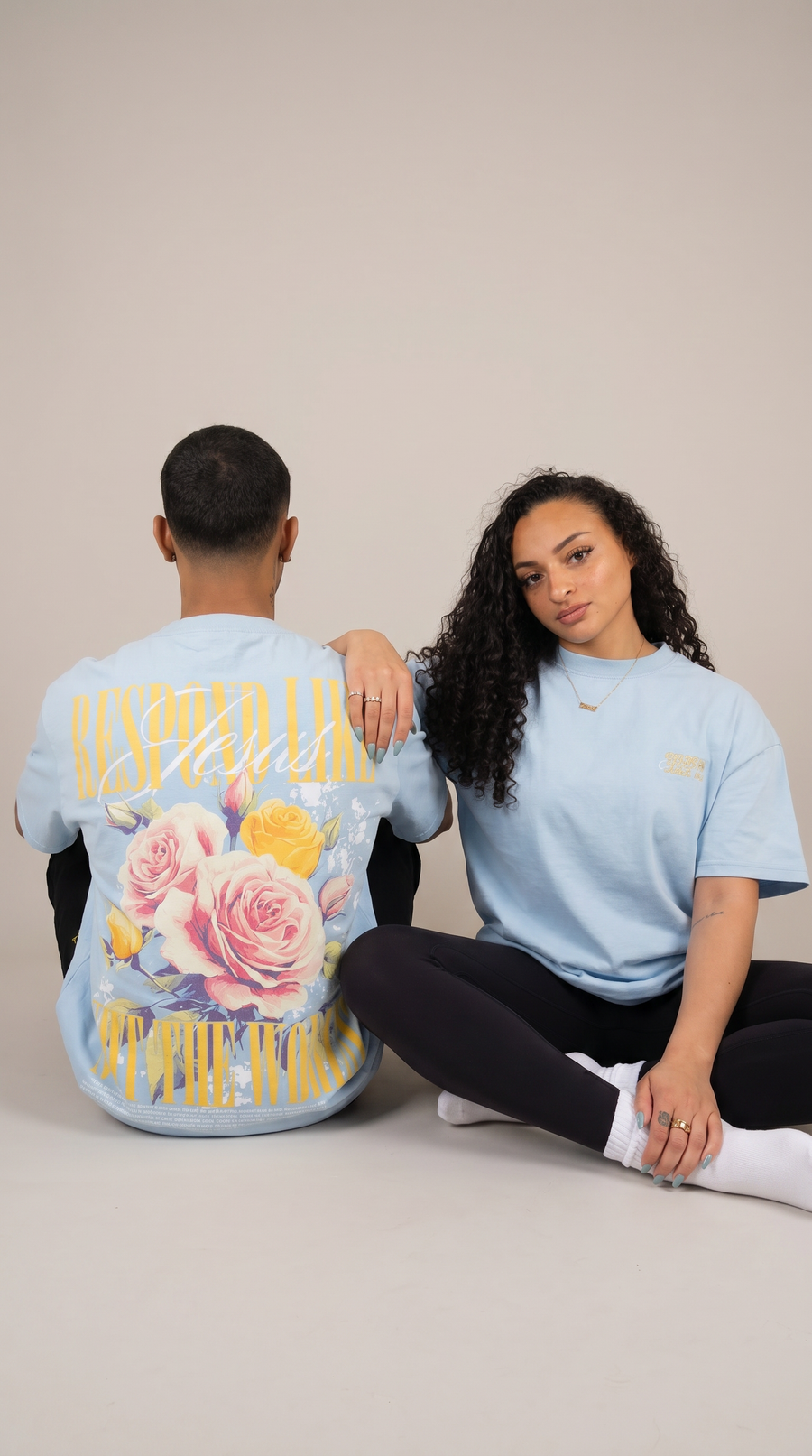 Woman wearing light blue "Respond Like Jesus" Christian tee with floral back graphic - sitting