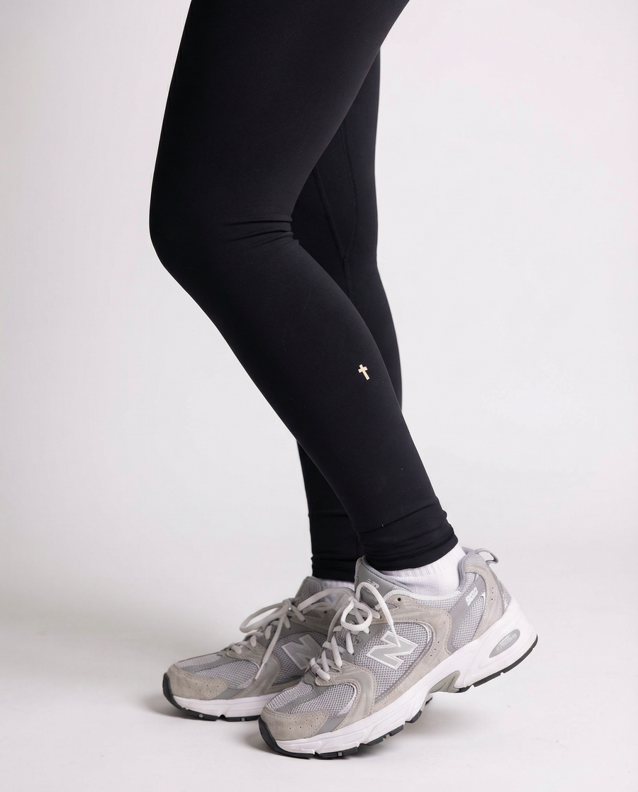 Black "I Believe" leggings paired with white sneakers - close-up