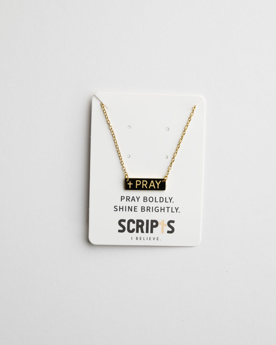 Close-up of gold "Pray" pendant necklace on display card