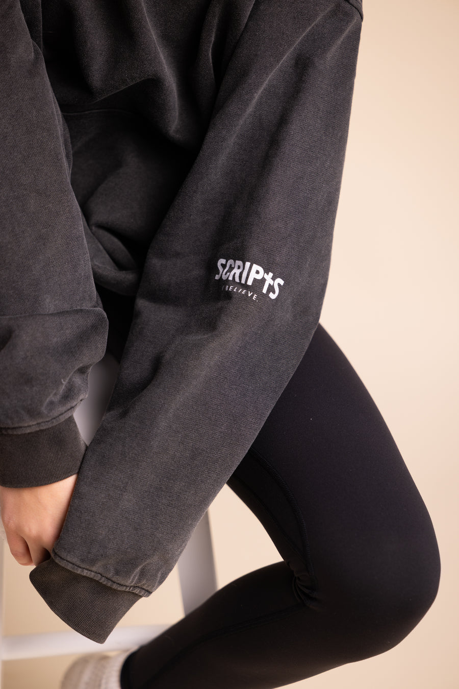 Close-up of "SCRIPTS" embroidered sleeve detail on black Christian hoodie