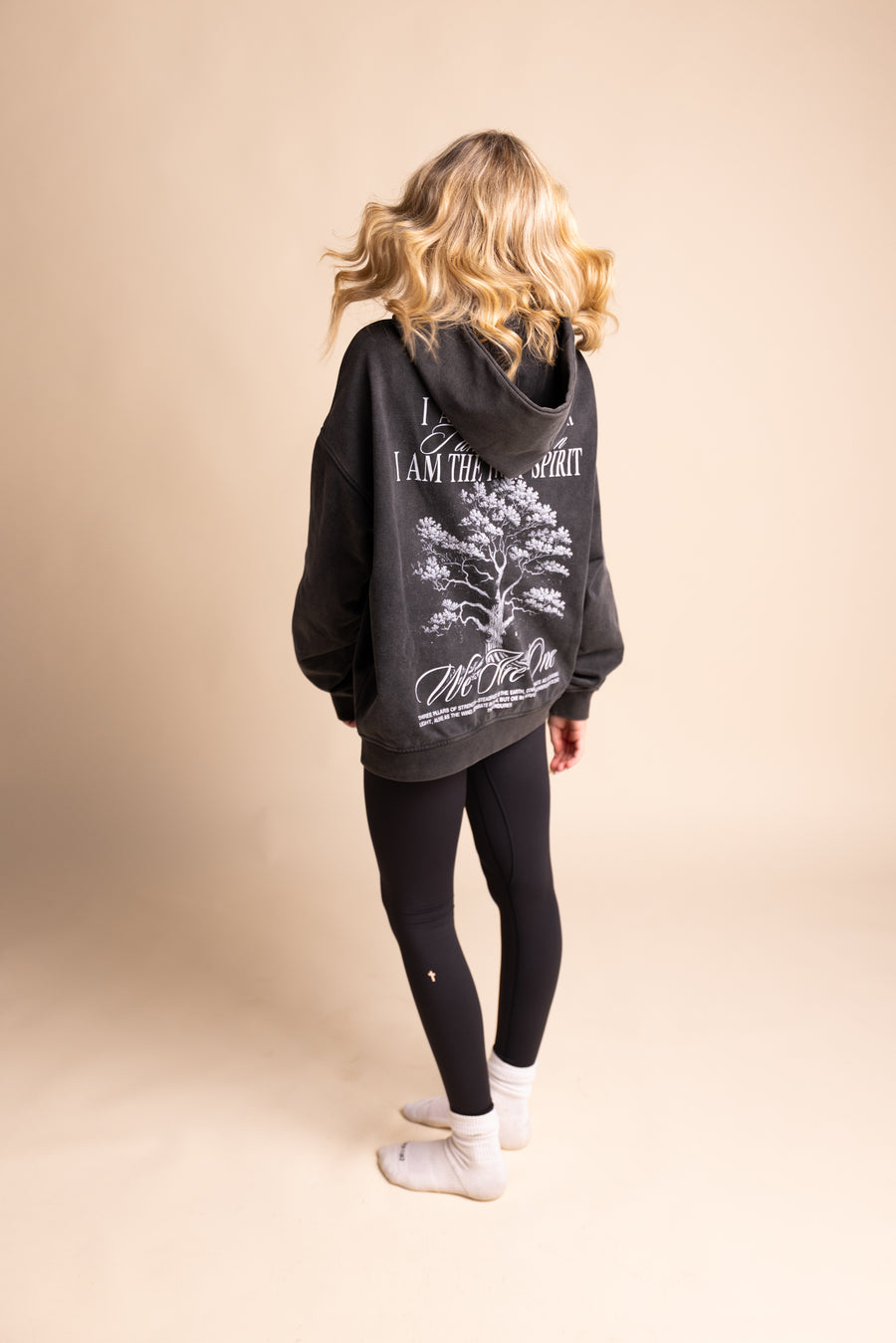 Woman wearing Christian "I Believe" leggings with faith-based graphic hoodie