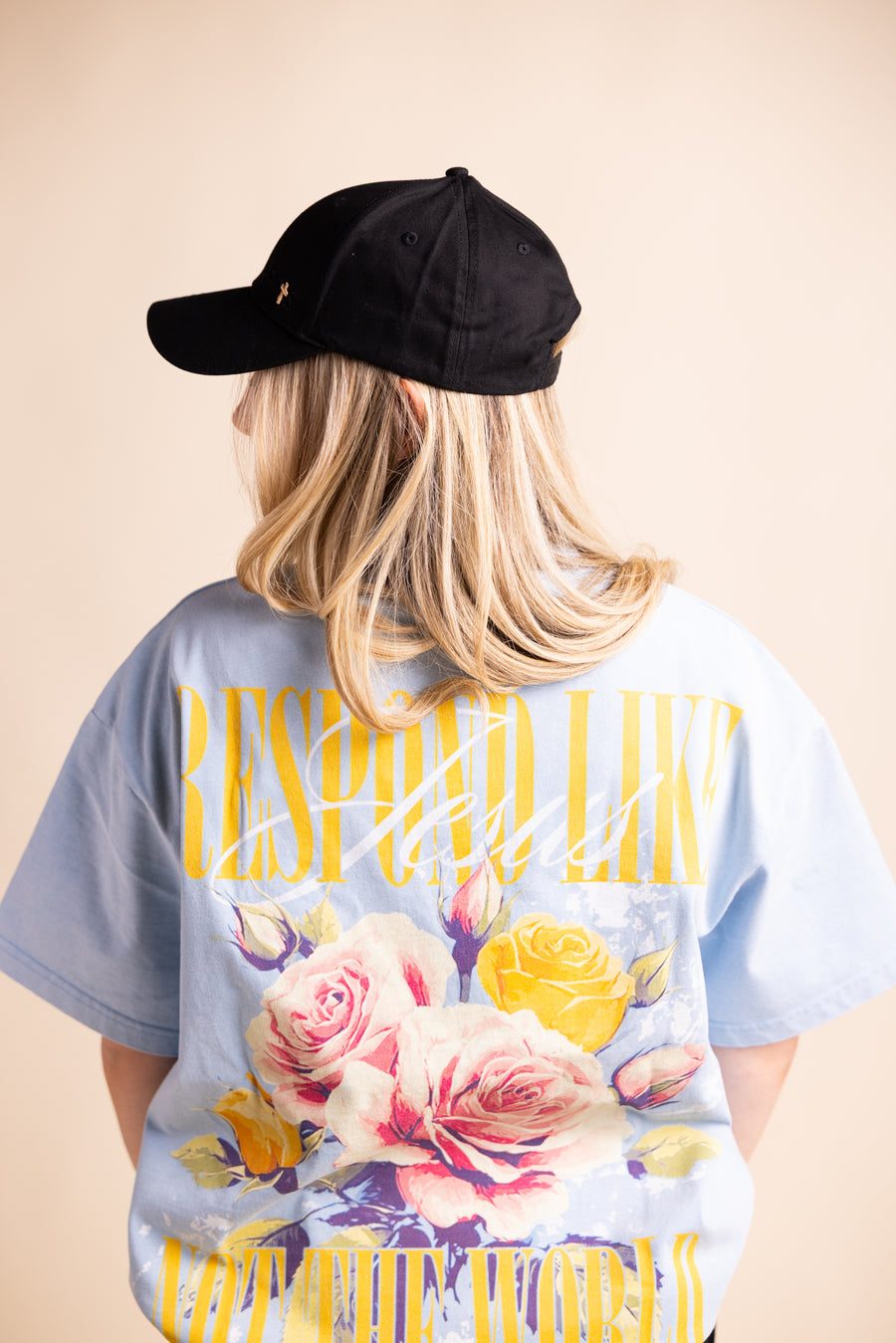 Woman wearing black cap and light blue "Respond Like Jesus" Christian tee - back view