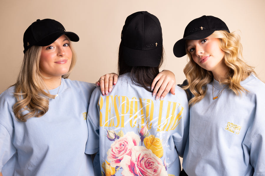 Three women wearing black caps and light blue "Respond Like Jesus" Christian tees - group shot