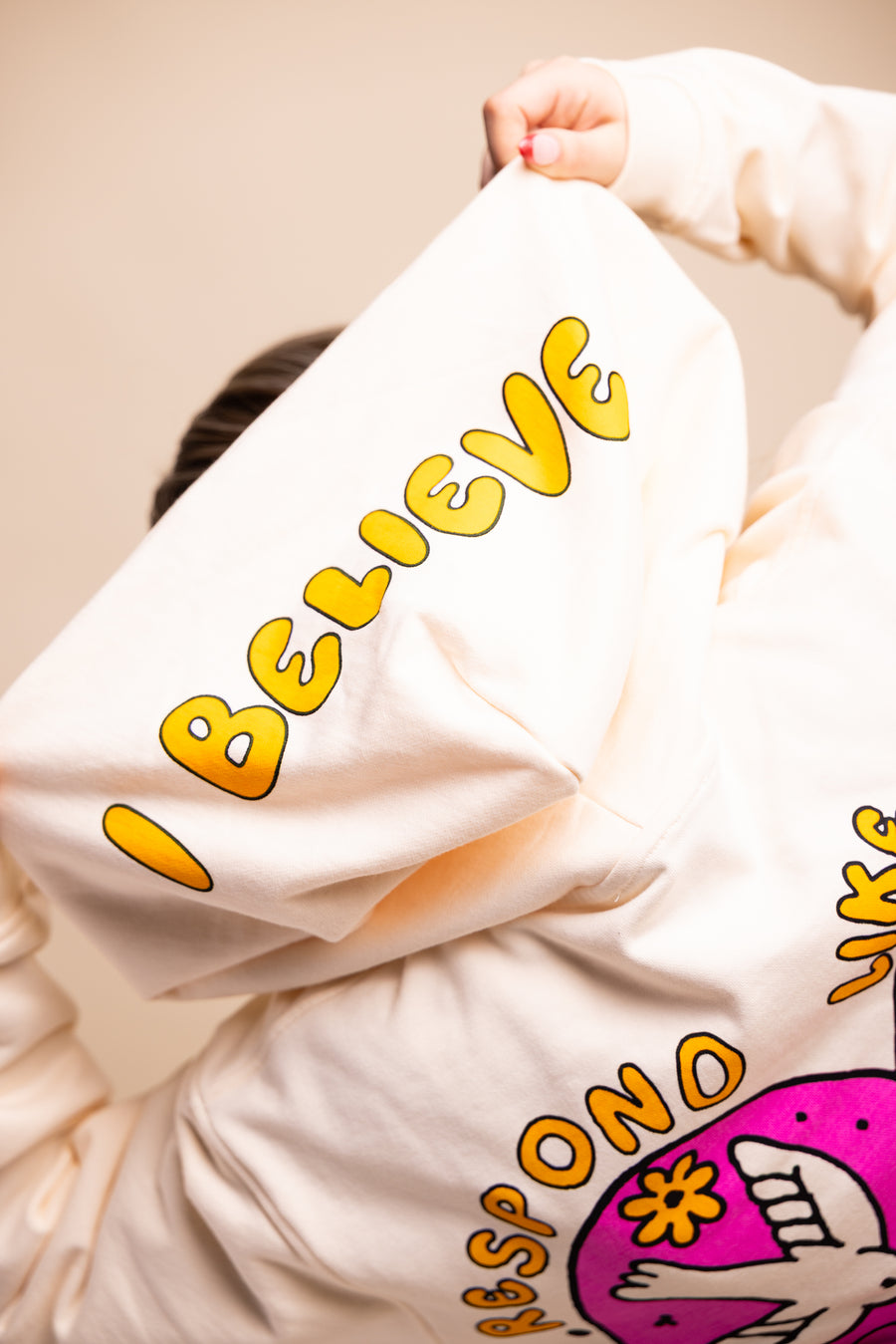Girl wearing Christian beige fleece hoodie with "I Believe" heart graphic - back view