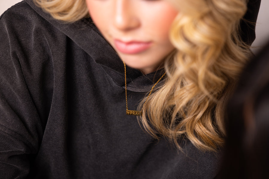 Christian "Pray" necklace worn close-up on woman