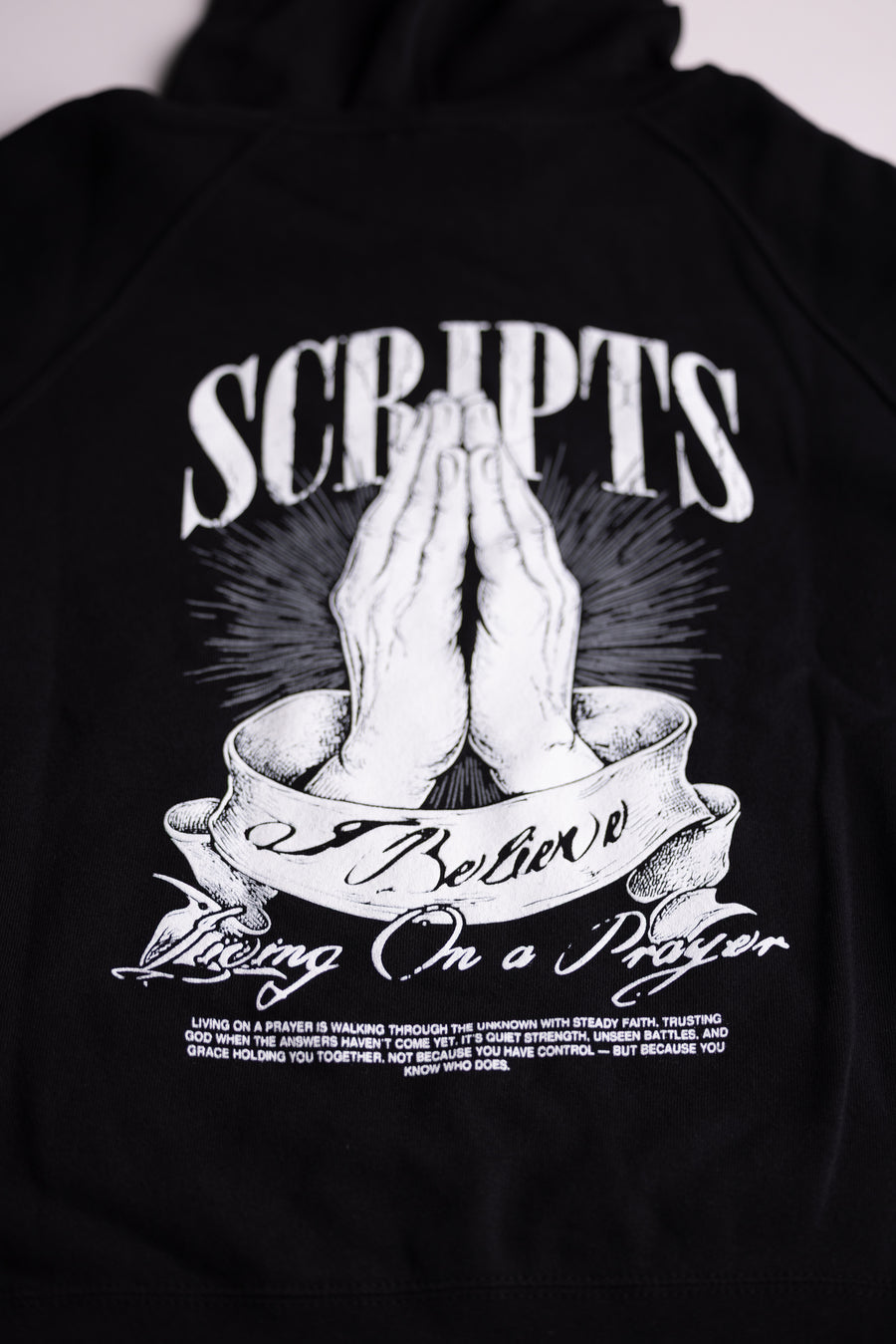 Close-up of Christian praying hands graphic on black youth hoodie