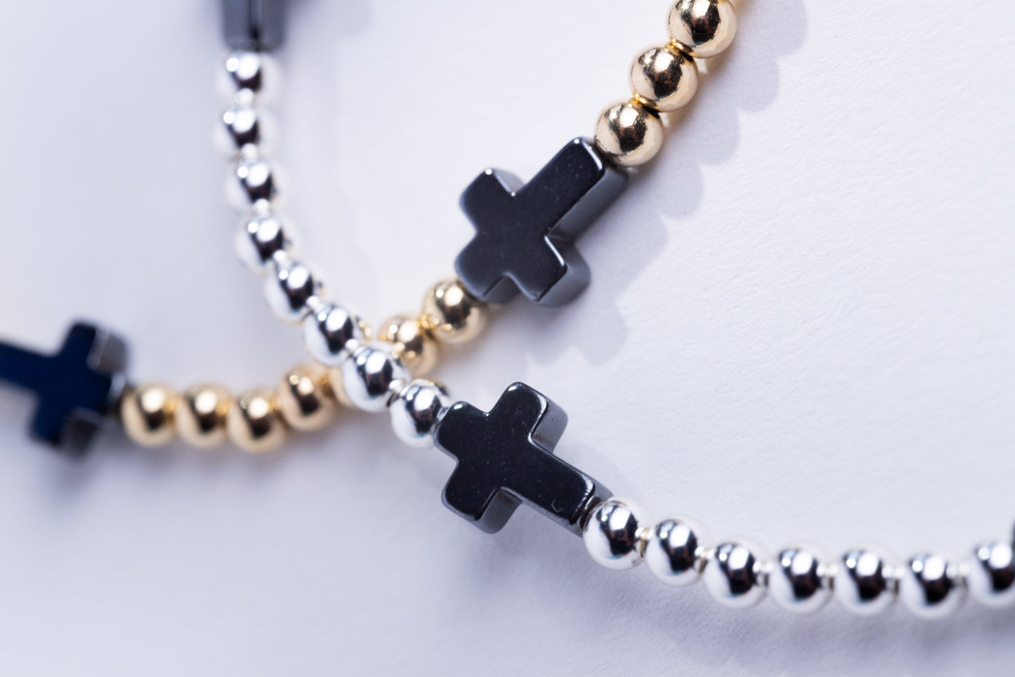 Bracelets with black cross charms on a light background